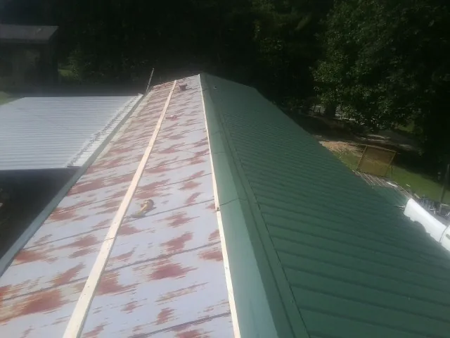 Old rusted panels beside newly installed green metal roofing — Wind Damage Roof Repair by Roofing Brothers in Manakin Sabot