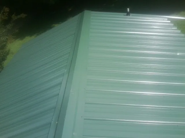 New green metal panels meeting at the ridge of a roof — Flat Roof Repair work by our crew in Manakin Sabot