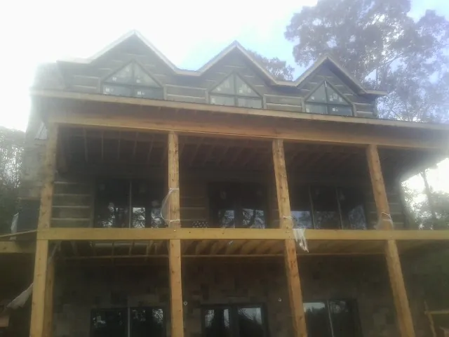 Dormers and porch framing on a large log home under construction — Roof Coating work by our crew in Manakin Sabot