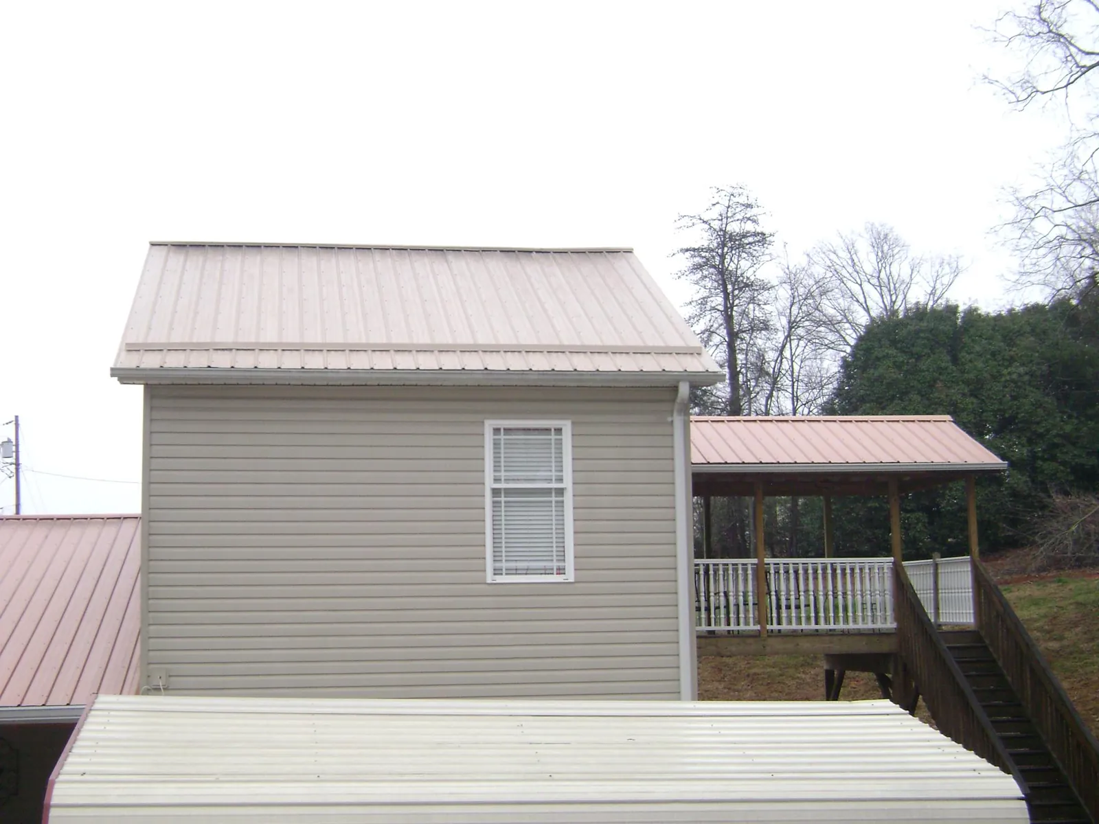 Tan metal roofs on a two story addition and attached porch, from a Roof Replacement job in Manakin Sabot