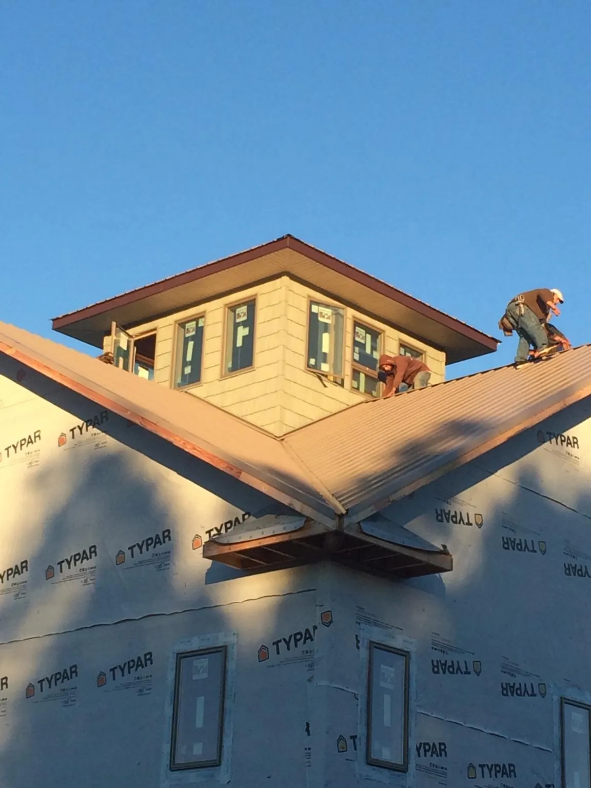 Roofers working around a rooftop cupola on a new metal roof at sunset — Roof Waterproofing in Manakin Sabot by Roofing Brothers